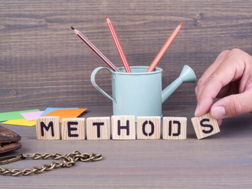 Wooden blocks spelling "METHODS" with pencils in a mint watering can