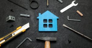 Tools arranged around blue house icon on dark background - home repair concept